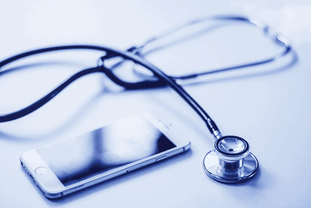 A blue stethoscope next to a mobile phone
